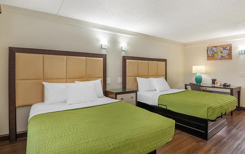 Guest room with two double beds, a work desk and a wall-mounted television